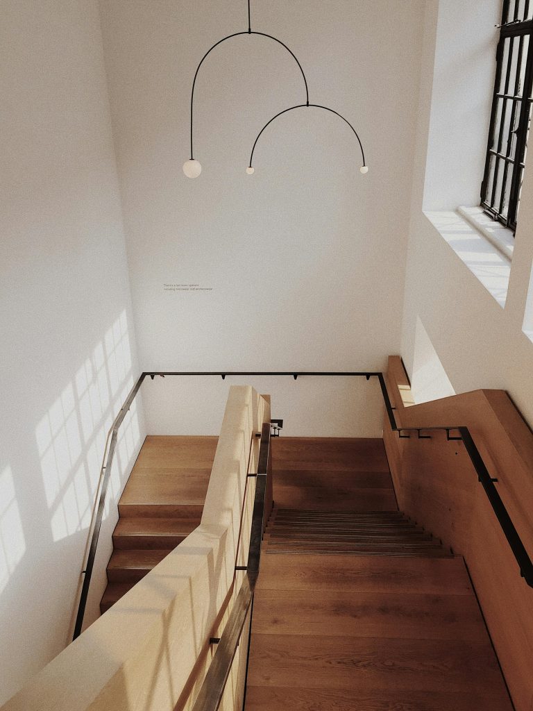 A minimalist interior featuring a wooden staircase with natural lighting and modern design elements.